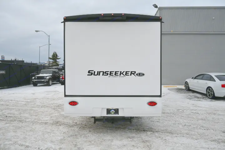 Rear view of a white Sunseeker RV rental. Parked on snowy ground with a Jeep & sedan nearby, ready for adventure.. Forest River Sunseeker - LE Series M-2850S 2024