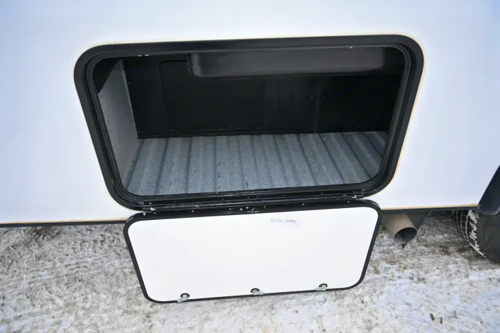 RV rental: Open side storage compartment showing its grey-lined interior. Snowy ground and exhaust pipe visible.. Forest River Sunseeker - LE Series M-2850S 2024