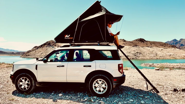 Your next adventure! This white SUV with a rooftop tent is perfect for an outdoor rv rental experience by the lake.. Ford Bronco sport 2022