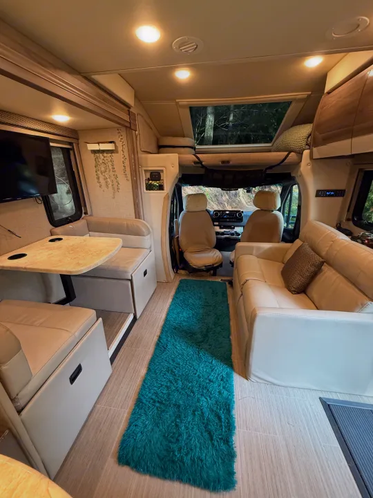Bright rv rental interior featuring dinette, sofa, and front cab. Ideal for comfortable RV travel and adventures.. Thor Delano Sprinter 2020