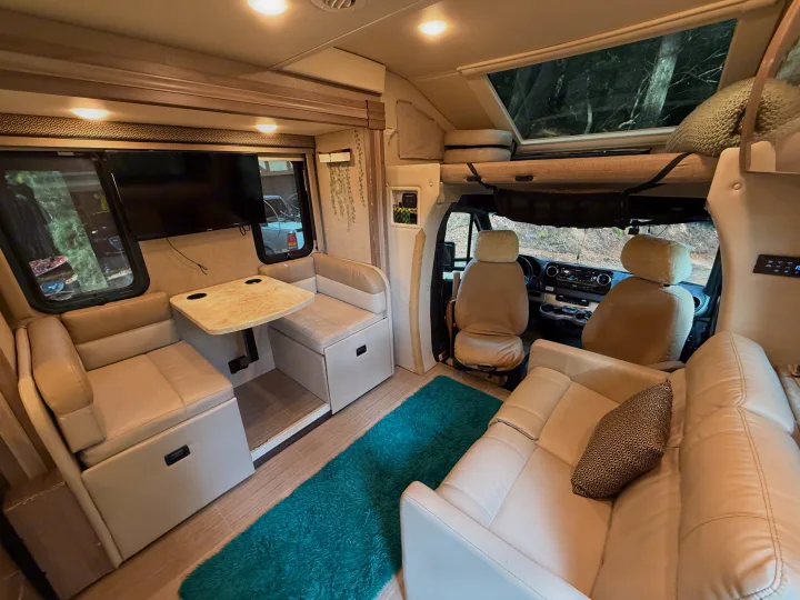 Step inside this RV rental's bright interior. Features include cream seating, dinette with TV, and a spacious cockpit area.. Thor Delano Sprinter 2020