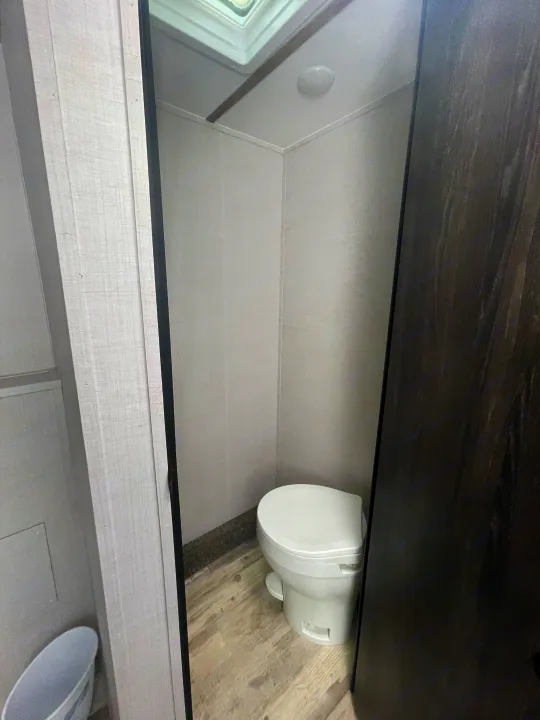 Inside an RV rental, a compact and clean bathroom features a white toilet, light walls, and a ceiling skylight.. Gulf Stream Innsbruck 2023