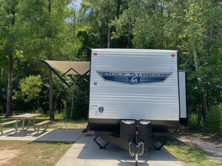 Gulf Stream RV rental at a scenic campsite with an extended awning and picnic table.. Gulf Stream Innsbruck 2023