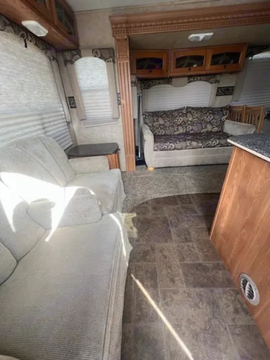 Inside an RV rental: comfortable living space with upholstered couches, wood cabinets, and durable tiled floor.. Heartland RVs North Trail 2011
