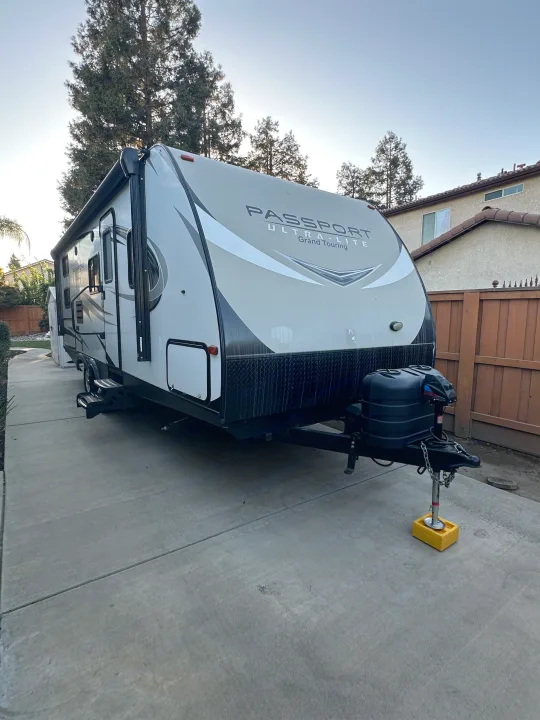 Front view of a white Passport Ultra-Lite travel trailer, parked on a driveway, ready for RV rental & road trips.. Keystone Passport 2019