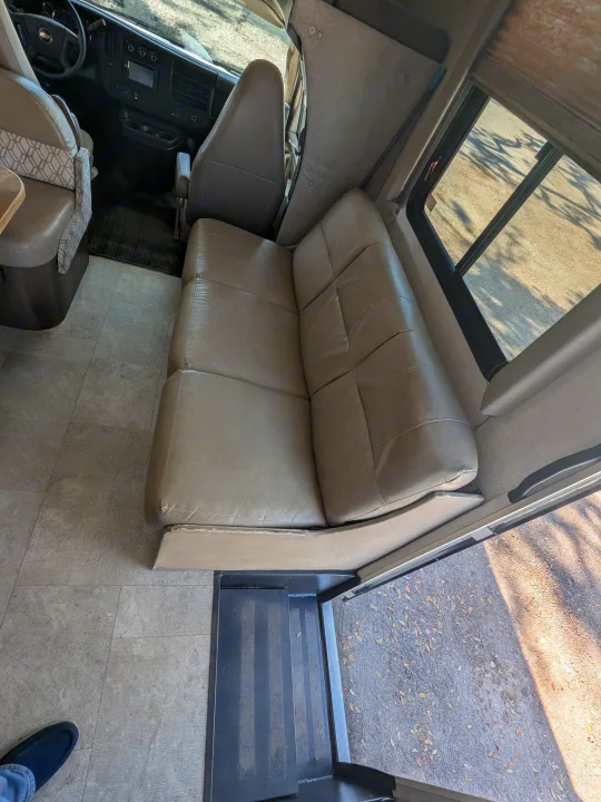 Inside an RV rental, showing the cockpit, main living area with a large sofa, and tiled floor leading to entry steps.. Coachmen Freelander 2018