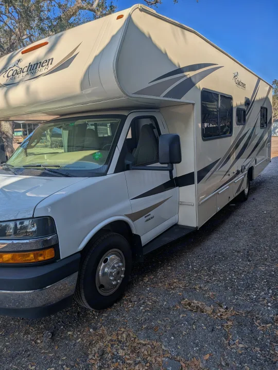 Coachmen Freelander Class C RV rental parked on gravel. This beige and white motorhome is ready for adventure.. Coachmen Freelander 2018