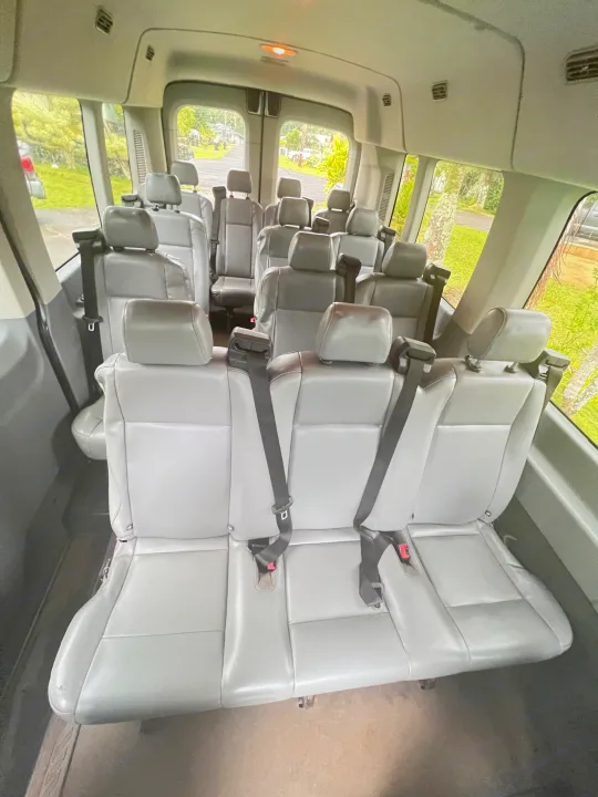 Spacious grey passenger van interior, great for group travel or RV rental excursions. Features multiple rows of comfortable seats with seatbelts.. Ford Custom Transit 2016