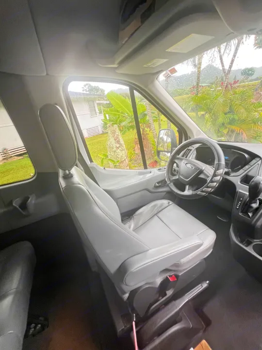 Spacious RV rental interior: Ford van cockpit with gray seats and a rainy tropical landscape view.. Ford Custom Transit 2016