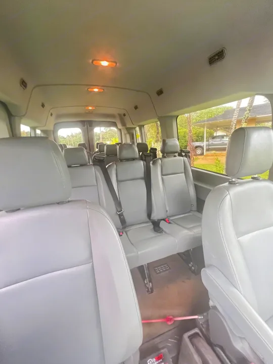 Spacious passenger van interior with gray seats & bright lights. Ideal for group trips, available through RV rental.. Ford Custom Transit 2016