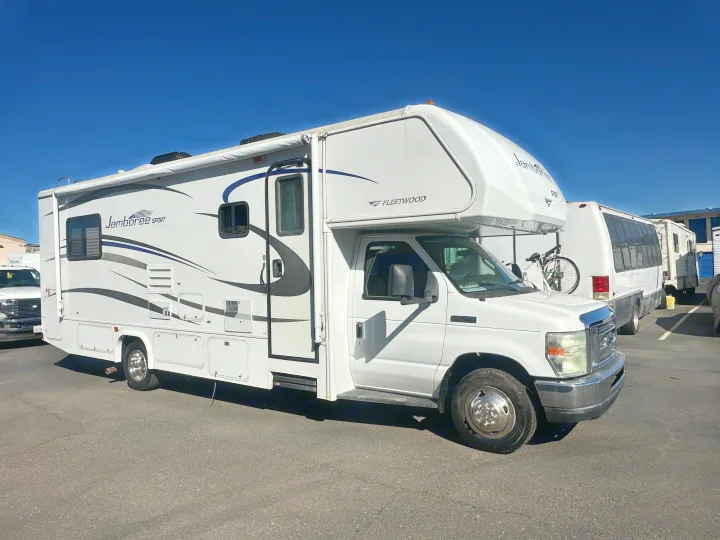 White Fleetwood Jamboree Sport Class C RV, a common rv rental, parked outdoors under clear blue sky.. Jamboree Sport 2010