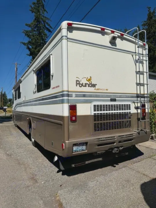 Rear view of a spacious cream & brown Fleetwood Pounder Turbo Diesel motorhome, an ideal rv rental for road trips.. Fleetwood 39/MH 2000