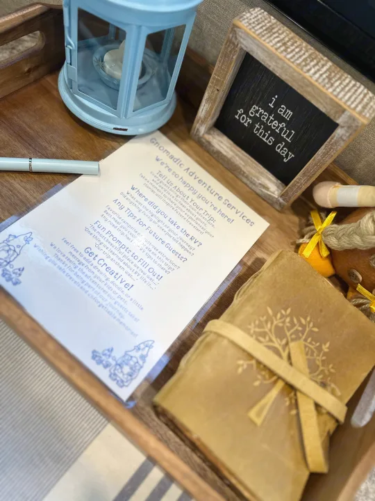 An RV rental guestbook, pen, and gratitude sign on a tray, inviting guests to share travel experiences.. Jayco Greyhawk 2019