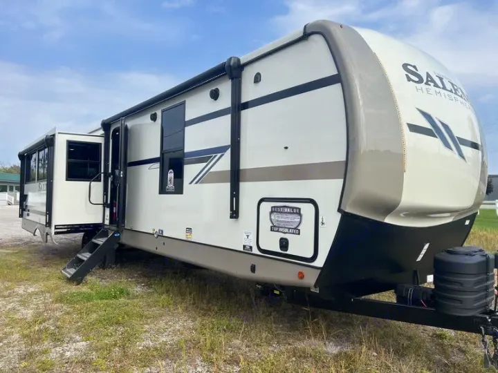 This large, cream-colored Salem Hemisphere travel trailer, ideal for RV rental, features an extended slide-out and entry steps.. Forest River Salem Hemisphere 2024