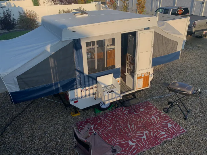 This Flagstaff pop-up camper RV rental is ready for camping, featuring an outdoor kitchen, grill, and patio mat.. Forest River Flagstaff 2000
