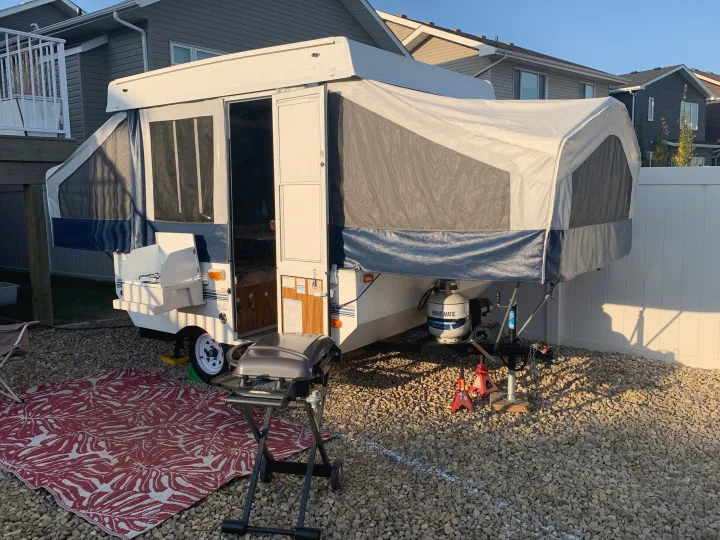 Pop-up RV rental setup: A spacious camper with an inviting outdoor rug and BBQ grill, perfect for backyard camping.. Forest River Flagstaff 2000