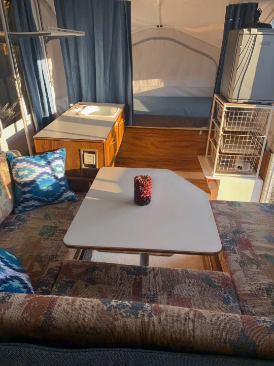 Cozy RV rental interior with a bright dinette table, kitchen sink, sleeping area, and storage. Ideal camper setup.. Forest River Flagstaff 2000