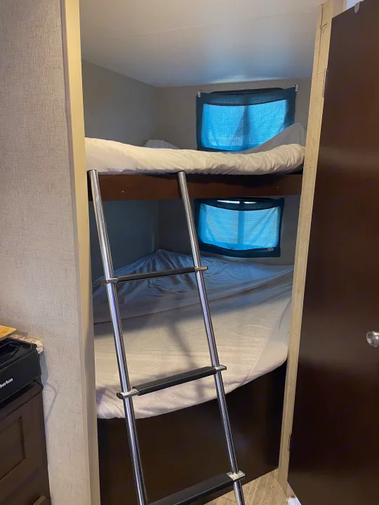 Inside an RV rental, a set of bunk beds with a ladder provides compact sleeping space.. Sportsmen Sportsmen Trailer 2017