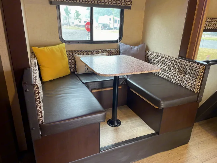 RV rental dinette features U-shaped seating with patterned backrests and dark cushions, plus a sturdy table.. Sportsmen Sportsmen Trailer 2017