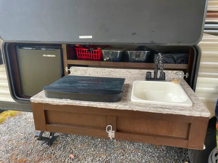 This RV rental features a convenient outdoor kitchen setup, complete with a sink, mini-fridge, and overhead storage.. Sportsmen Sportsmen Trailer 2017