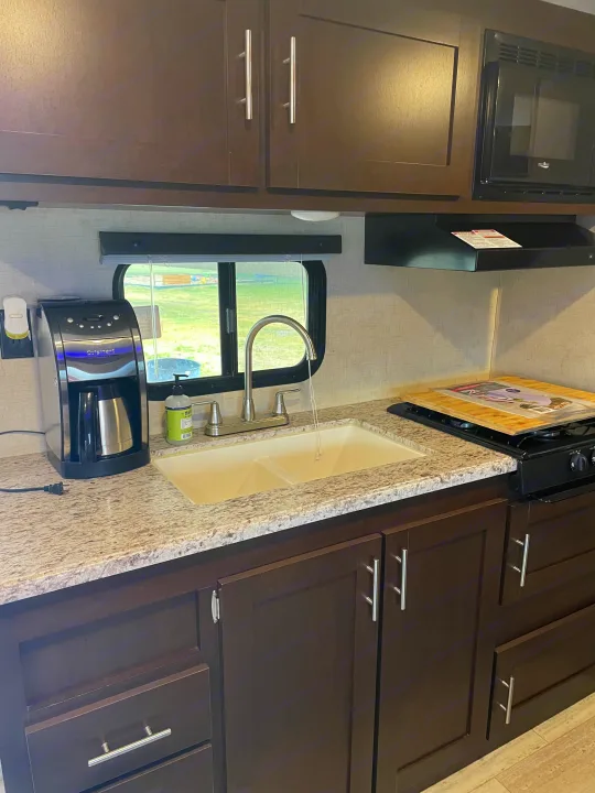 RV rental interior: modern kitchen with dark cabinets, granite counters, sink, coffee maker, and appliances.. Sportsmen Sportsmen Trailer 2017