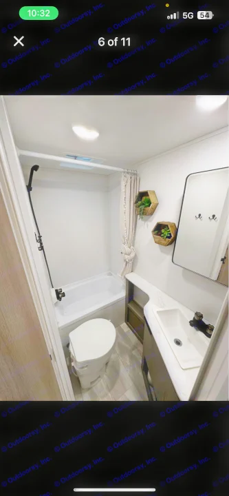 Compact RV rental bathroom featuring a shower-tub combo, toilet, vanity with sink, mirror, and decorative shelves.. Dutchmen Kodiak SE 2024
