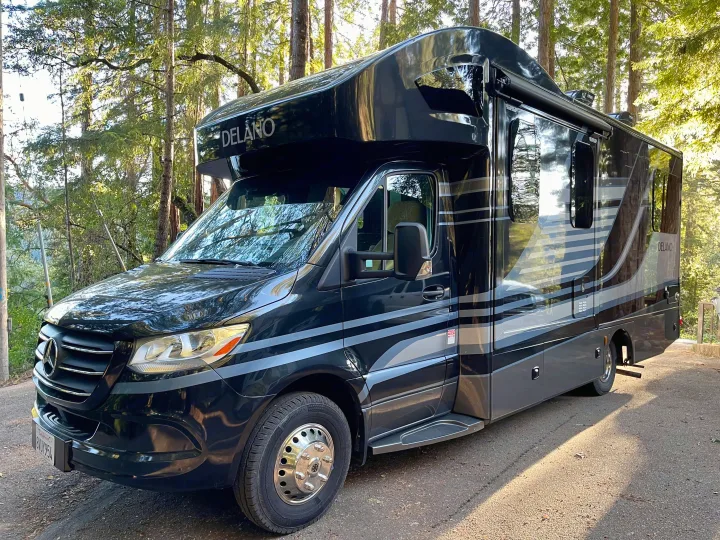 Luxury Mercedes-Benz Delano RV rental parked in a sunlit forest, ready for adventure.. Thor Delano Sprinter 2020