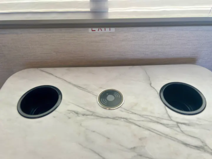 Modern RV rental interior: faux marble countertop with two cup holders, a built-in wireless charger, and an exit sign.. Thor Coleman 2024