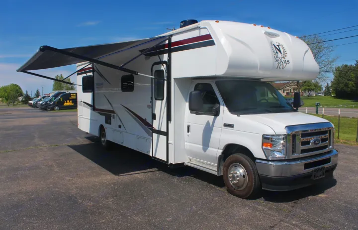 White Nexus Triumph motorhome rv rental with extended awning, parked on asphalt.. Nexus RV Triumph 2021