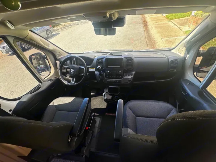 RV rental: Ram ProMaster van interior, showing the driver's area with steering wheel, dashboard, and front seats.. Winnebago Solis 2023