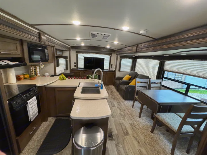 Modern RV rental kitchen, dining, and living area. Features appliances, comfortable seating, and bright windows.. Keystone RV Cougar X-Lite 2018