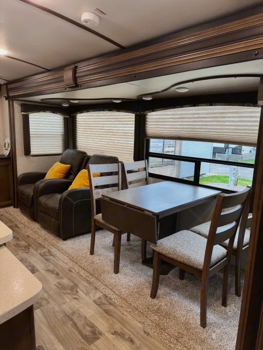 Experience comfort in this RV rental's living/dining area, featuring plush recliners, a versatile dining table, and bright windows.. Keystone RV Cougar X-Lite 2018