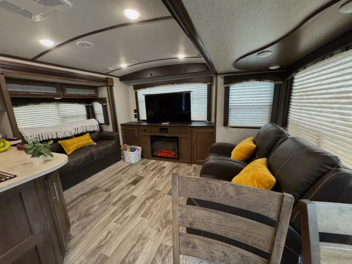 Experience comfort in this RV rental's inviting interior: living area with a fireplace, TV, and kitchen space.. Keystone RV Cougar X-Lite 2018