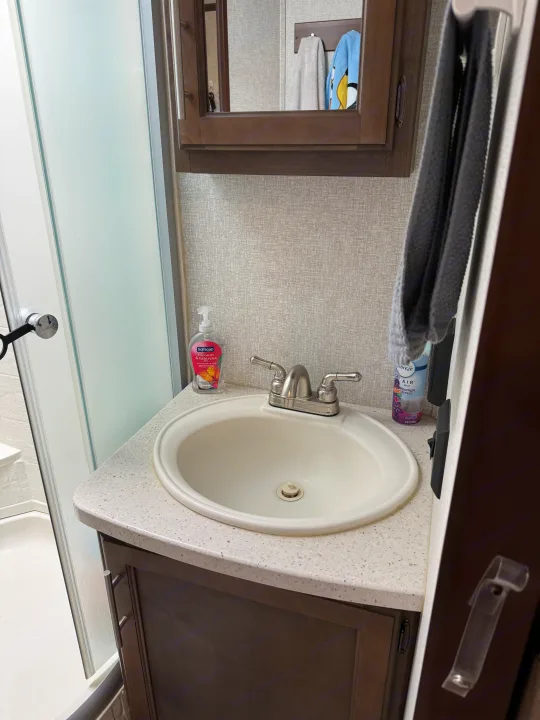 RV rental bathroom vanity featuring a sink, Softsoap, Febreze, and a nearby shower stall. Compact and clean.. Keystone RV Cougar X-Lite 2018