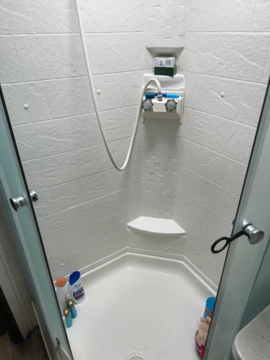 Inside an RV rental: a compact shower with white textured walls, handheld showerhead, and toiletries.. Keystone RV Cougar X-Lite 2018