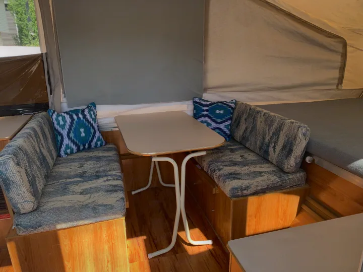 RV rental: Bright pop-up camper dinette with patterned blue cushions, a table, and light wood flooring.. Forest River Palomino 2003