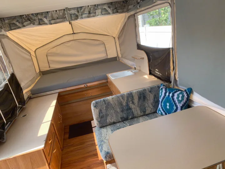 Cozy pop-up rv rental interior with bed, dinette, and sink, perfect for camping adventures.. Forest River Palomino 2003