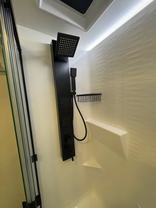 Modern black multi-jet shower system in a clean, brightly lit RV rental shower with textured walls.. Brinkley 295 AIR 2025