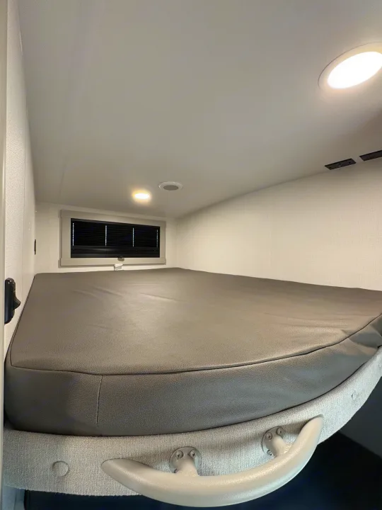 Cozy RV rental bunk bed interior with a grey mattress, window, and ceiling lights, ideal for resting.. Brinkley 295 AIR 2025