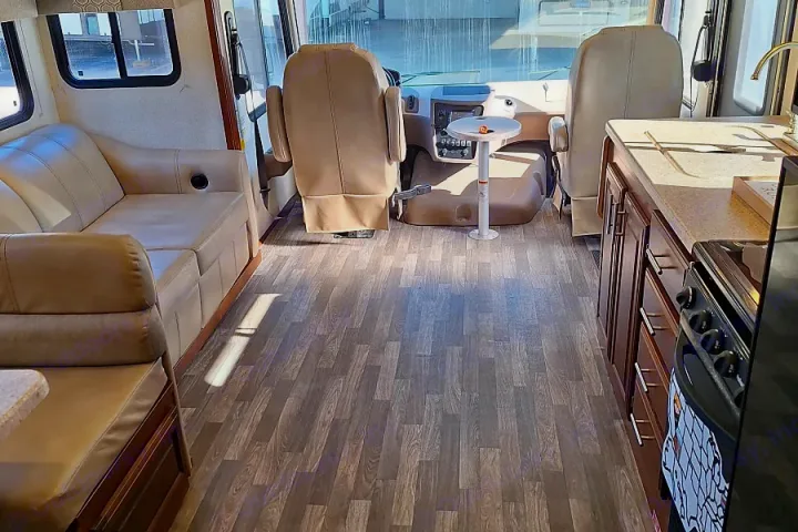 Spacious RV rental interior with wood-look floor, beige seating, kitchenette, and cockpit view, showing a clean, modern design.. FR3 FR3 Motorhome 2018