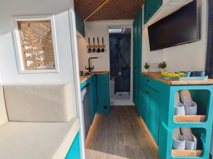 Efficient RV rental camper van interior. Features include a kitchen with teal cabinets, cozy seating, and a compact bathroom.. Peugeot Boxer L4H2 2021