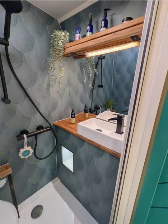 Compact RV rental bathroom features stylish teal scalloped tiles, a wooden vanity with sink, and modern black fixtures.. Peugeot Boxer L4H2 2021