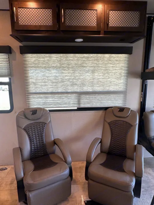 RV rental interior: Two comfy recliners, overhead cabinets, and window blinds for a relaxing journey.. Grand Design Momentum 2022