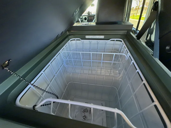An open vehicle fridge/cooler with wire baskets inside an RV rental, perfect for road trips.. Jeep Overlander 2019