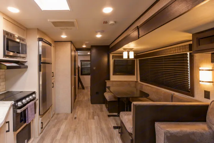 Modern RV rental interior, highlighting the kitchen with appliances, dining booth, and hallway leading to other rooms.. Jayco Jayflight 32BHDS.G 2022