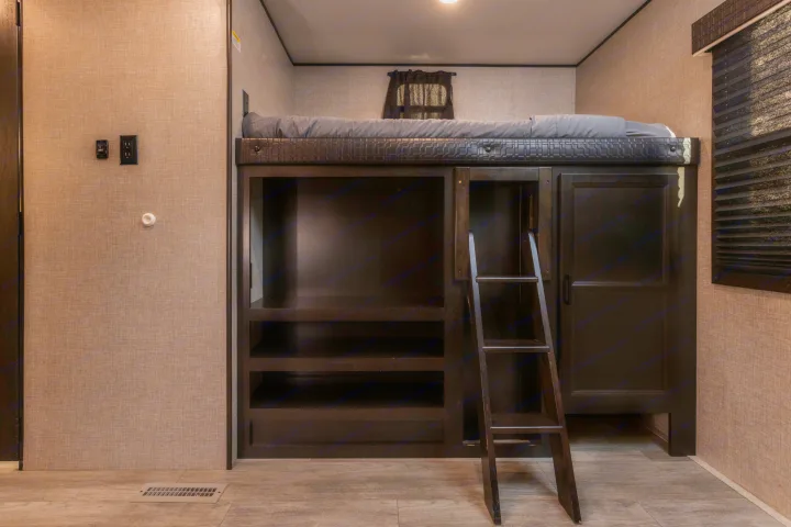 Cozy rv rental bunk bed with ladder, built-in shelves, and a gray mattress, set in a neutral-toned interior.. Jayco Jayflight 32BHDS.G 2022
