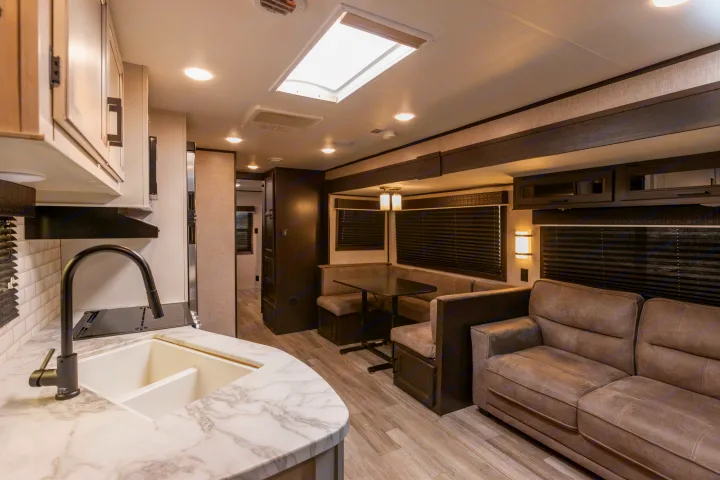Inside an RV rental: kitchen with sink & marble counters, a cozy dinette, sofa, and wood-look floors. Bright and inviting.. Jayco Jayflight 32BHDS.G 2022