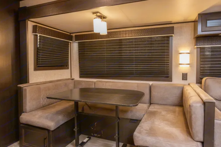 An inviting RV rental interior featuring a U-shaped dinette, dark table, and privacy blinds.. Jayco Jayflight 32BHDS.G 2022