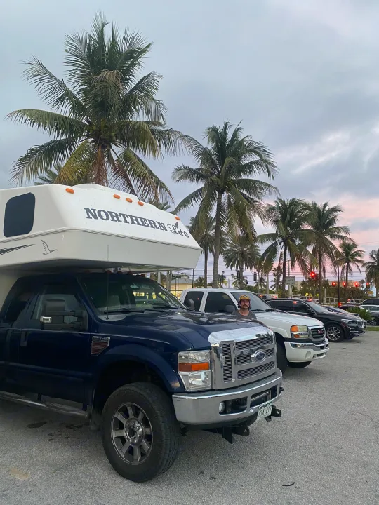 A blue Ford F-350 with a Northern Lite truck camper, ideal for your next RV rental adventure parked near palm trees.. Northern Lite 9-6 Wet Bath 2022