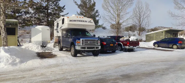 Snowy outdoor scene featuring an RV truck camper, other vehicles, and buildings. Ideal for an RV rental winter trip.. Northern Lite 9-6 Wet Bath 2022